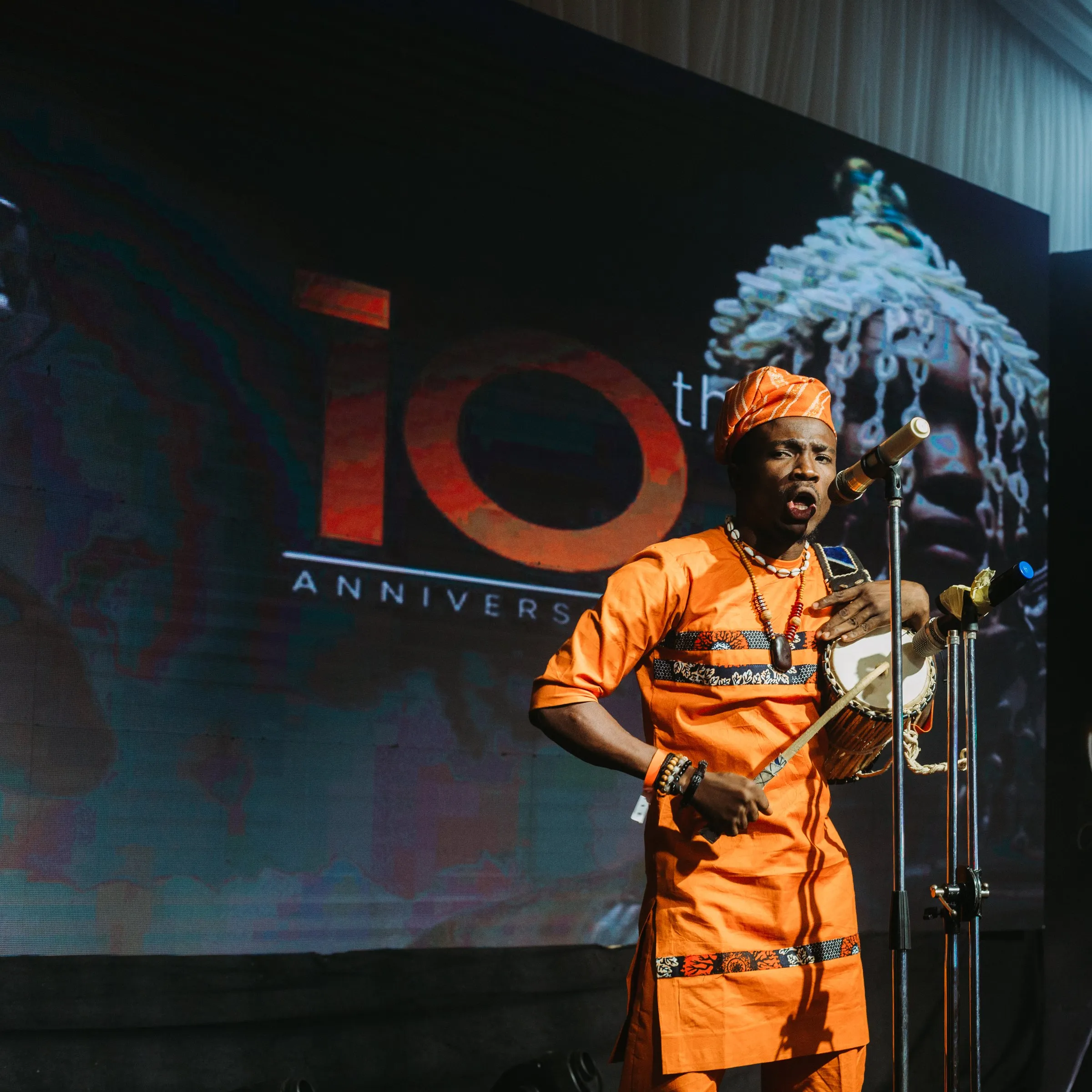 Song and talking drum, with the anniversary screen behind